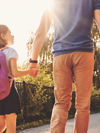 père de famille marchant avec ses 3 enfants qui se donnent la main